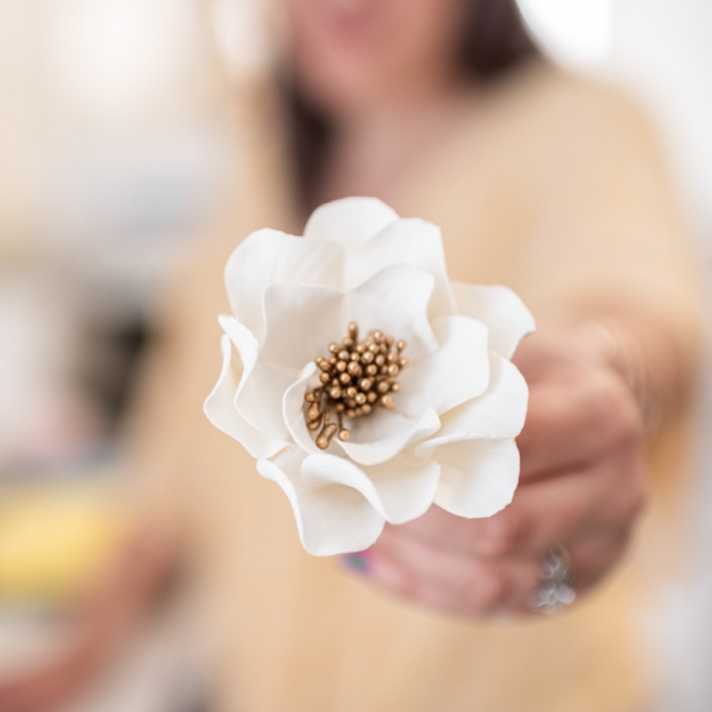 woman holding white and gold open rose sugar flower