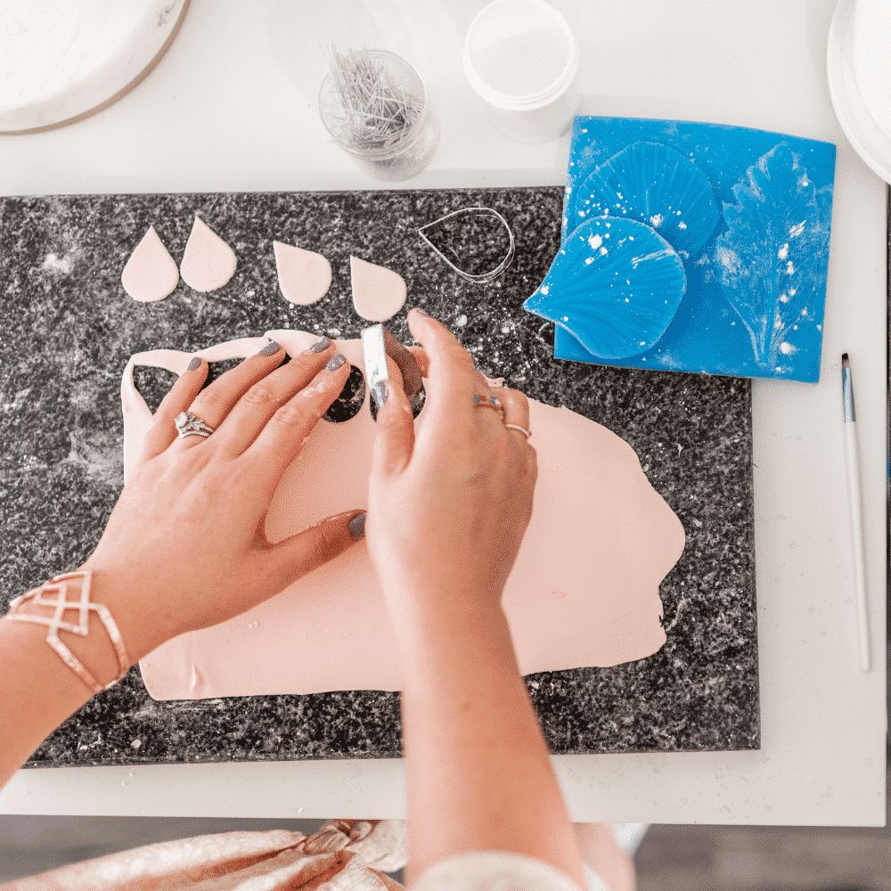 hands cutting out rose petals from rolled out pink gumpaste