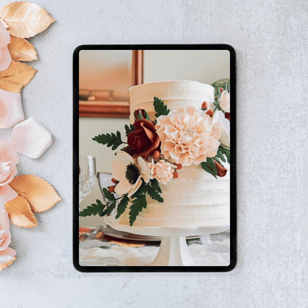 ipad on a gray surface showing a photo of a two tier cake with sugar flowers