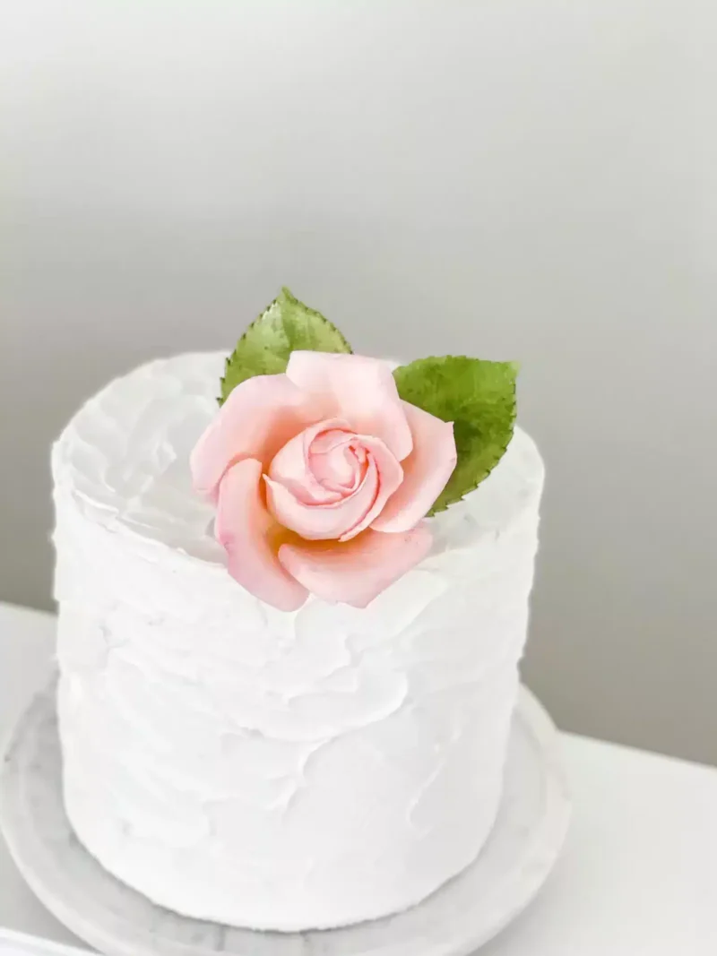 small blush rose sugar flower cake topper sitting on a 6 inch one tier cake