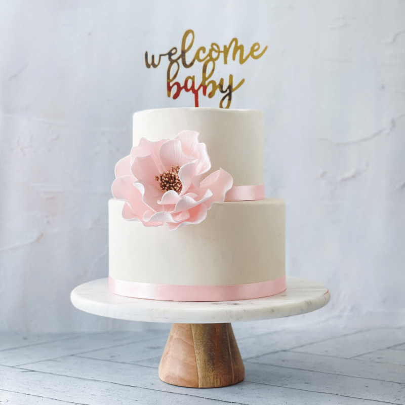 extra large blush and gold open rose sugar flower on a two tier white fondant baby shower cake