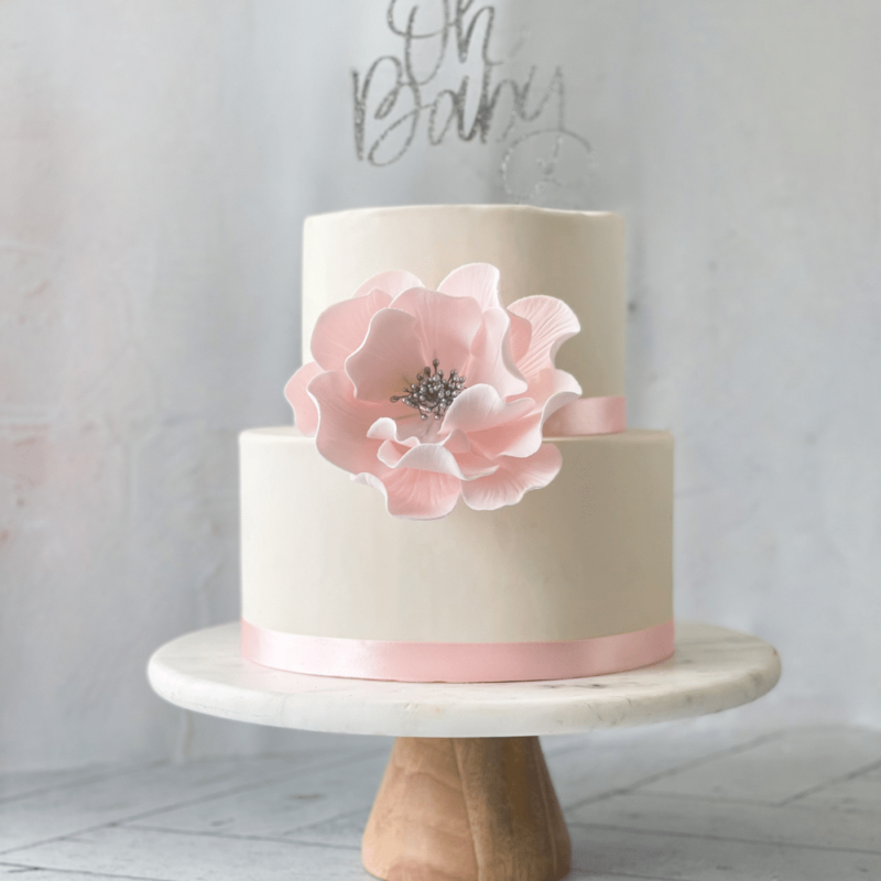 extra large blush and silver open rose sugar flower on a two tier white fondant baby shower cake