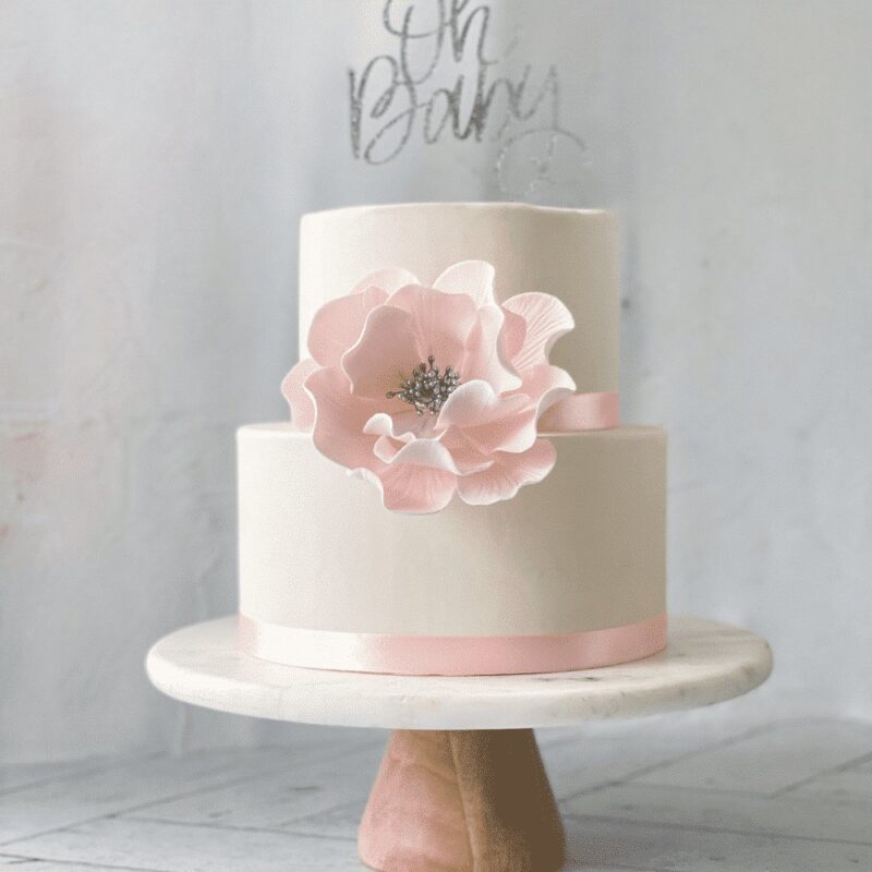 extra large blush and silver open rose sugar flower on a two tier white fondant baby shower cake