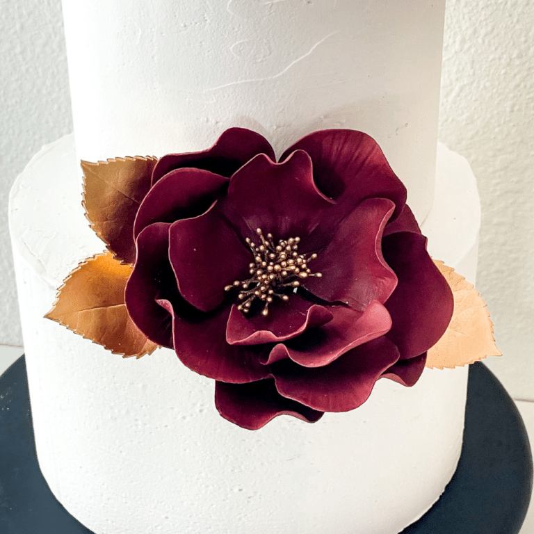 extra large burgundy and open rose sugar flower with gold leaves on graduation cake