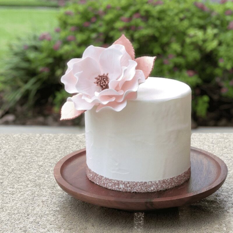 small buttercream cake with large blush open rose sugar flower and rose gold leaves