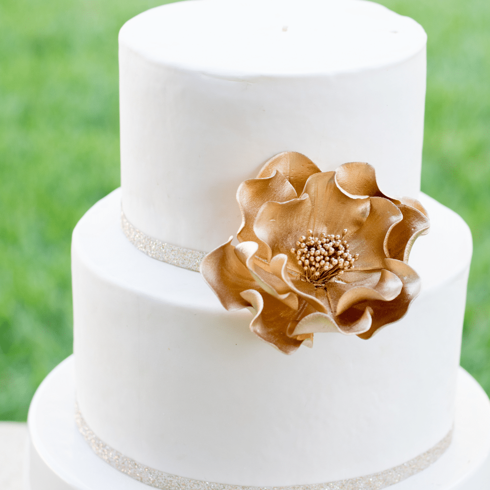 large gold open rose sugar flower close up on a two tier cake