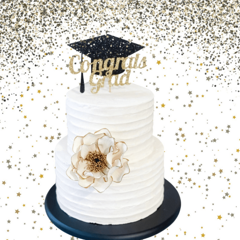 white and gold edged open rose sugar flower on a two tier buttercream cake with a graduation cake topper