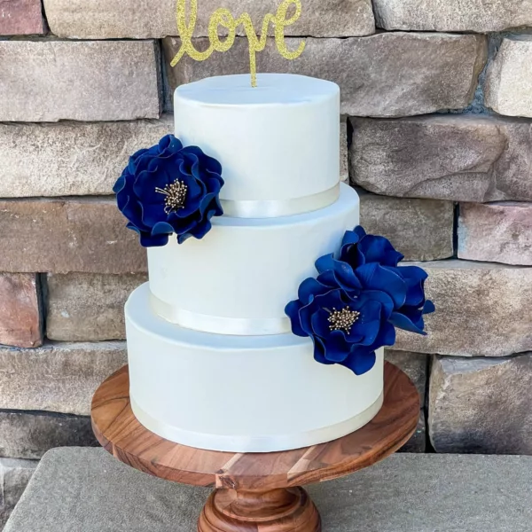 Set of four navy open roses on a three tier cake with gold stamen centers