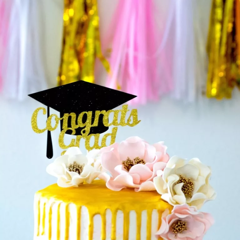 open roses sugar flowers decorating a gold drip graduation cake