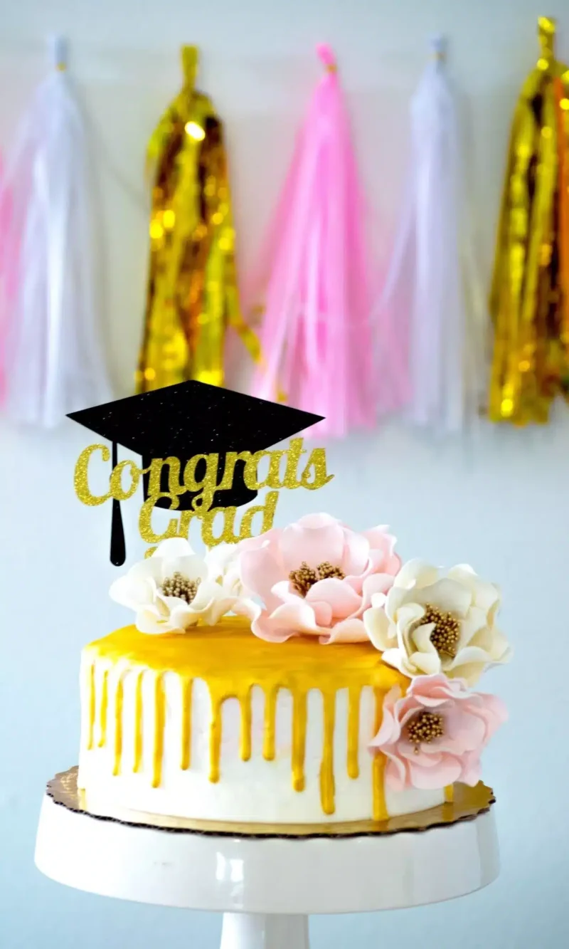 open roses sugar flowers decorating a gold drip graduation cake