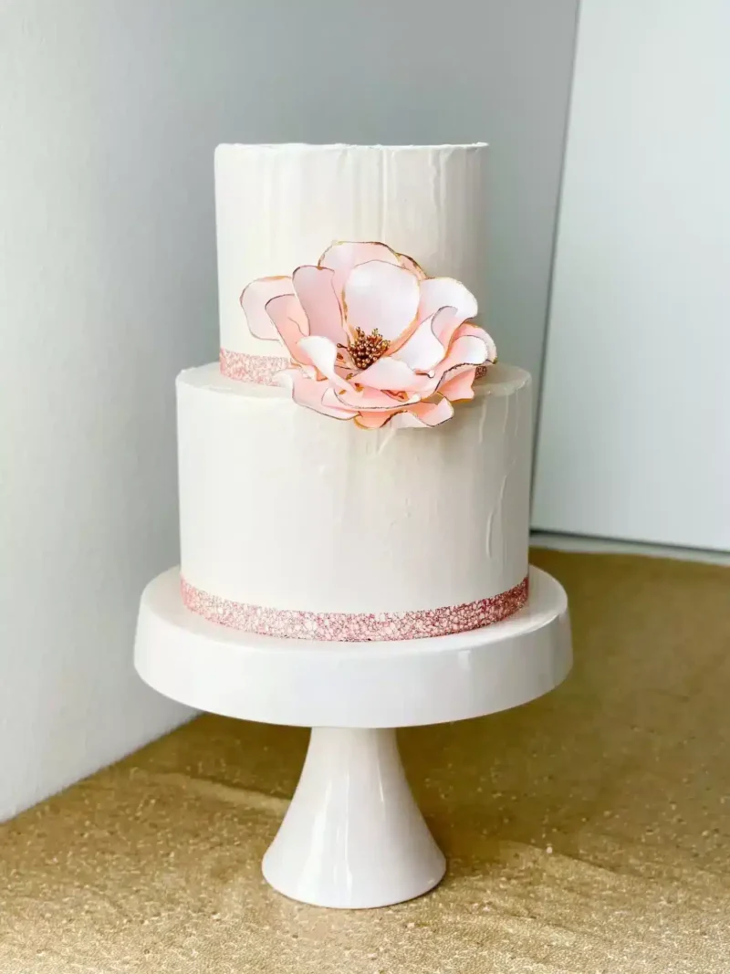 extra large blush gold edged open rose sugar flower on a two tier white fondant wedding cake