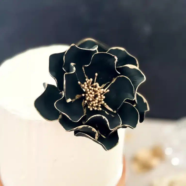large black and gold edged open rose on a small buttercream cake