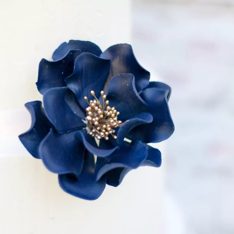 Close up of small navy and gold open rose gumpaste flower