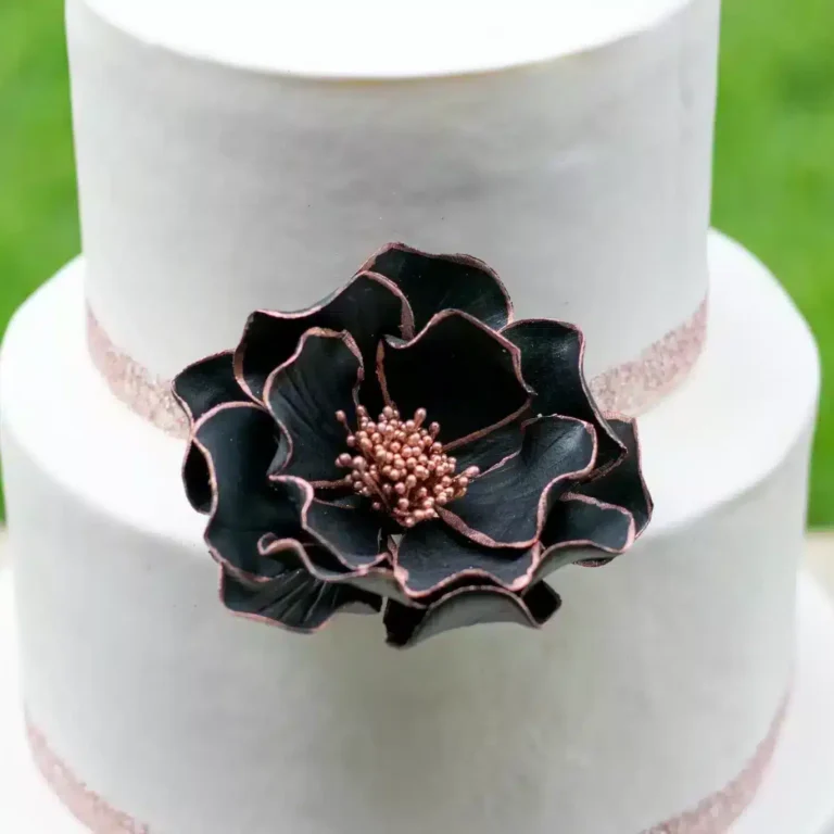 rose gold edged open rose sugar flower on a two tier white fondant wedding cake