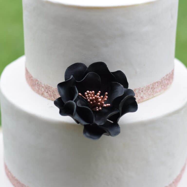 small black rose gold open rose sugar flower on a two tier white fondant wedding cake