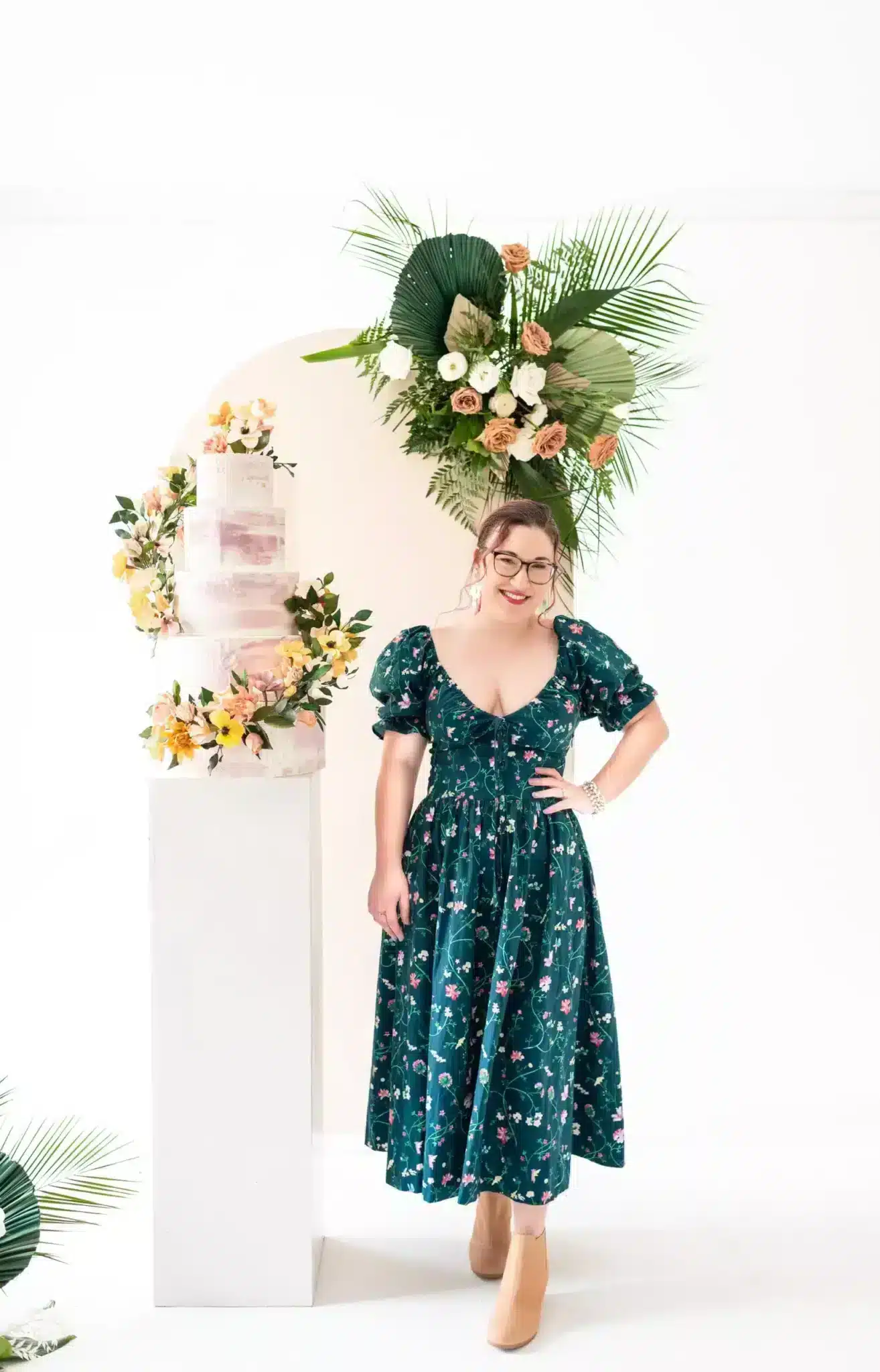 sugar artist standing next to wedding cake with sugar flowers