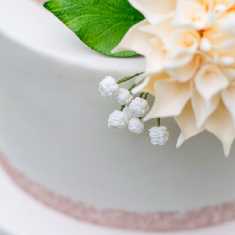 gypsophila flowers also known as baby's breath gumpaste flowers shown close up on a fondant wedding cake next to a dahlia gumpaste flower