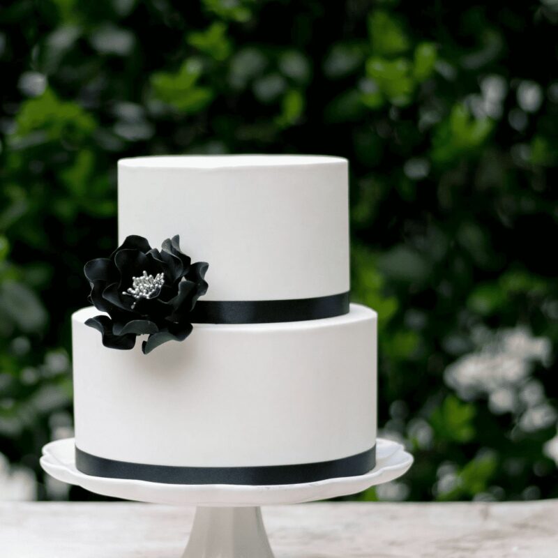 medium black and silver open rose sugar flower on a two tier white fondant wedding cake