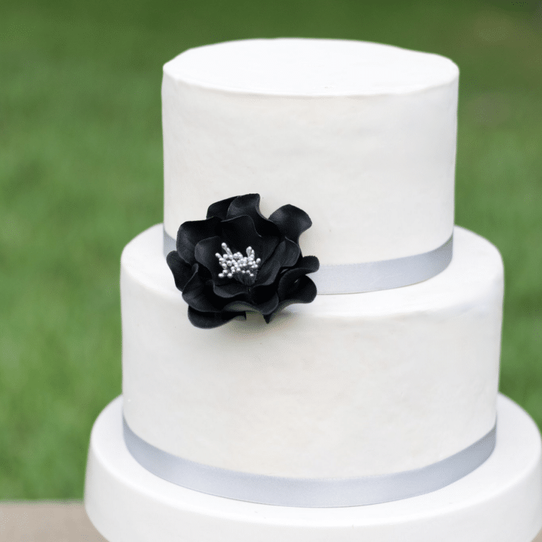 small black and silver open rose sugar flower on a two tier white fondant wedding cake