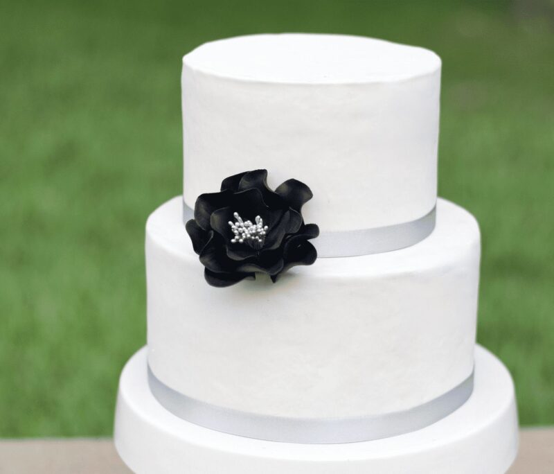 small black and silver open rose sugar flower on a two tier white fondant wedding cake