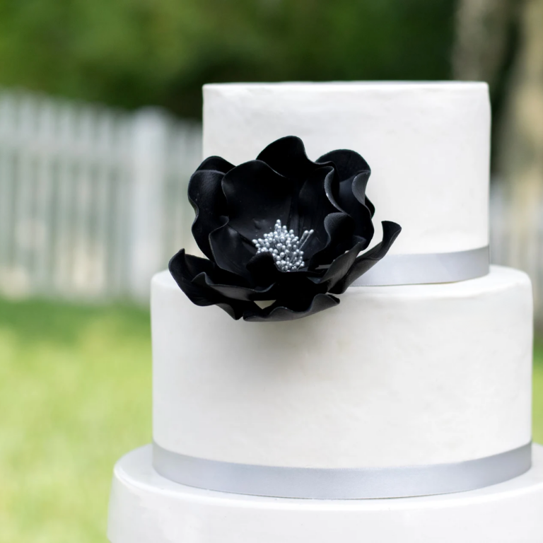 extra large black and silver open rose sugar flower on a two tier white fondant wedding cake