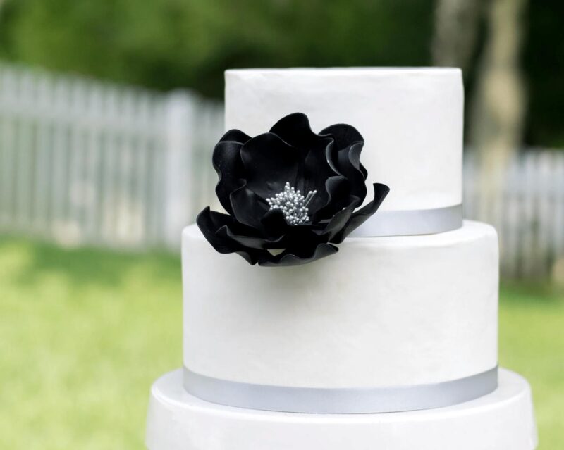 extra large black and silver open rose sugar flower on a two tier white fondant wedding cake