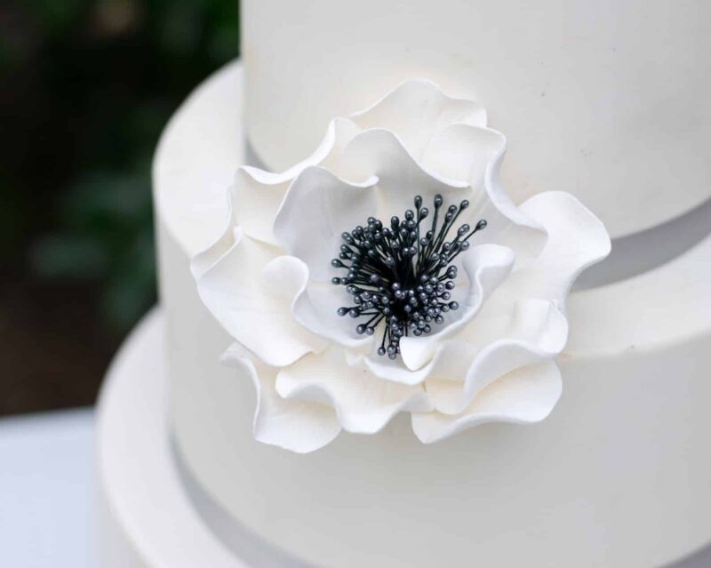 extra large white and black open rose sugar flower on a two tier white fondant wedding cake