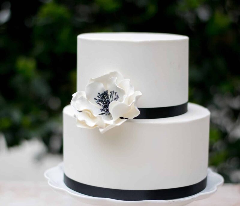 white and black large open rose sugar flower on a two tier white fondant wedding cake