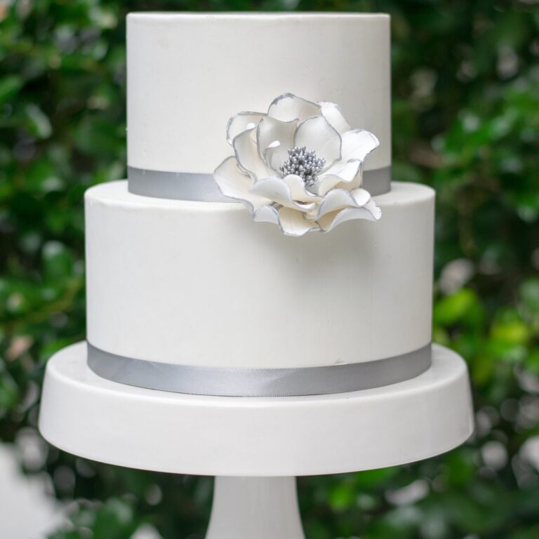 medium silver edged white open rose sugar flower on a two tier white fondant wedding cake