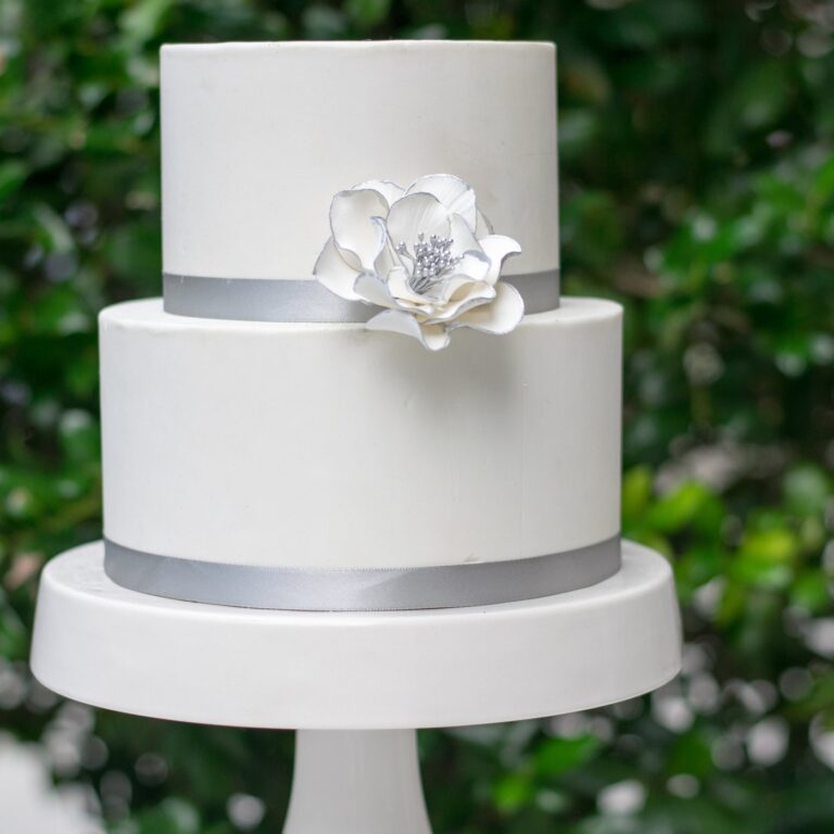 small white silver edged open rose sugar flower on a two tier white fondant wedding cake