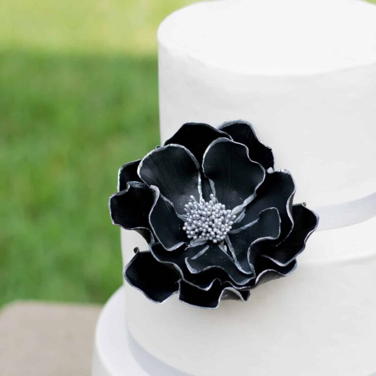 extra large black and silver edged open rose sugar flower on a two tier white fondant wedding cake