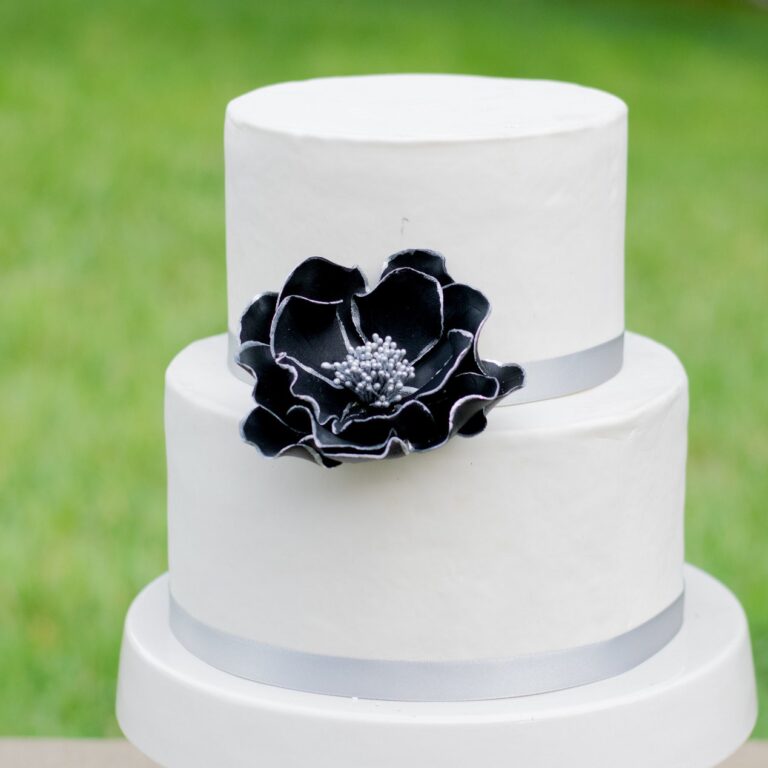 large black and silver edged open rose sugar flower on a two tier white fondant wedding cake