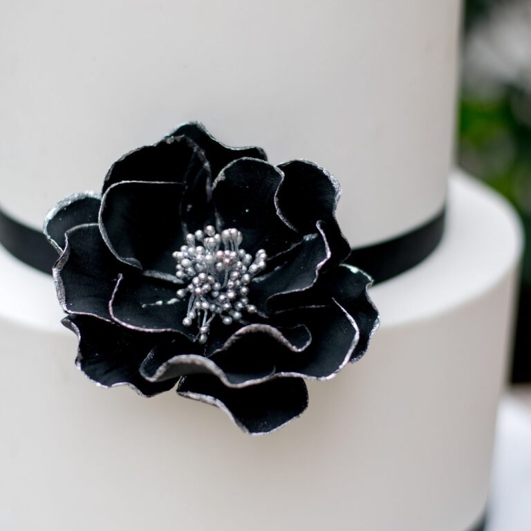 medium black and silver edged open rose sugar flower on a two tier white fondant wedding cake