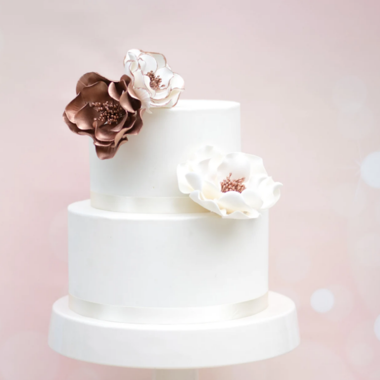 rose gold open rose sugar flowers on a two tier white fondant wedding cake