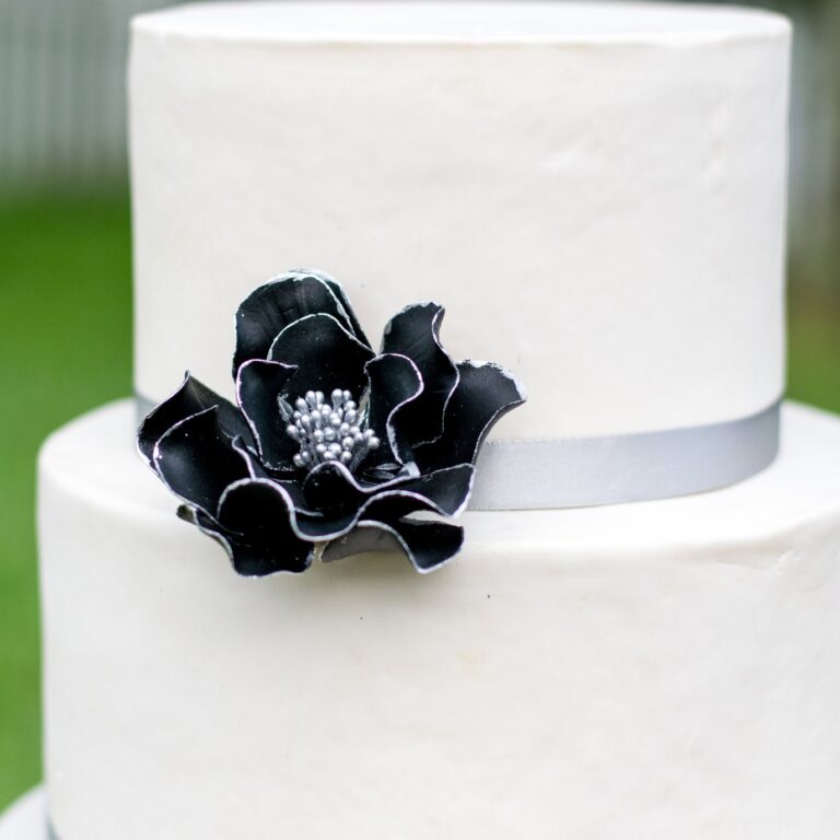small black and silver edged open rose sugar flower on a two tier white fondant wedding cake