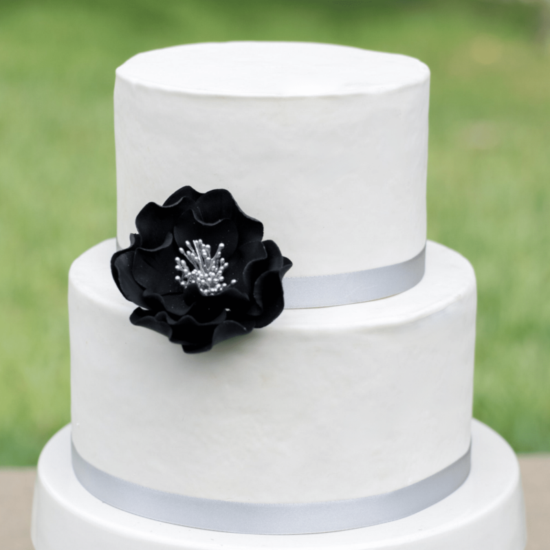 medium black and silver open rose sugar flower on a two tier white fondant wedding cake