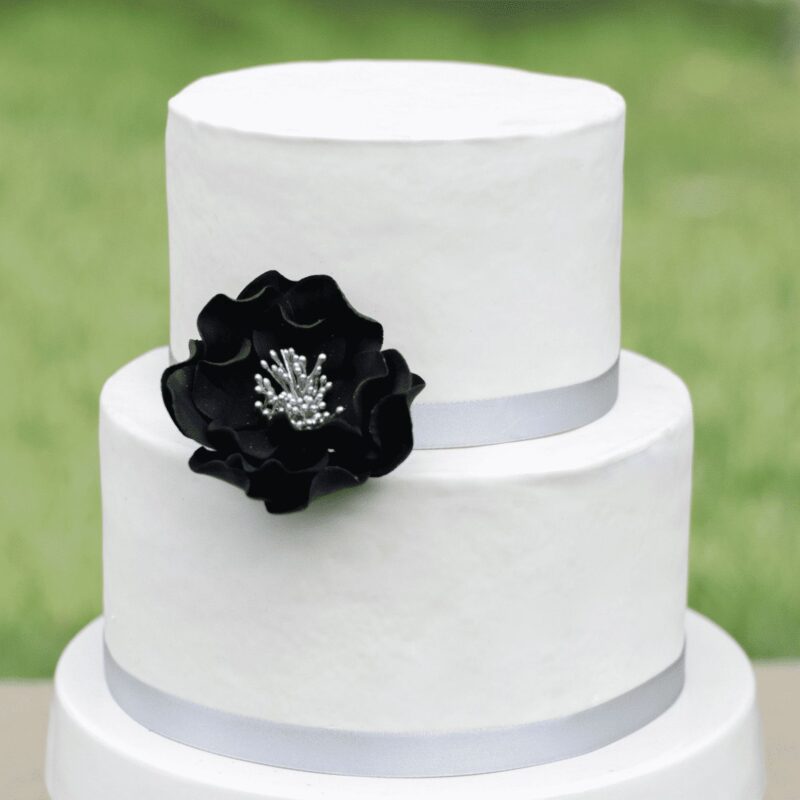 medium black and silver open rose sugar flower on a two tier white fondant wedding cake