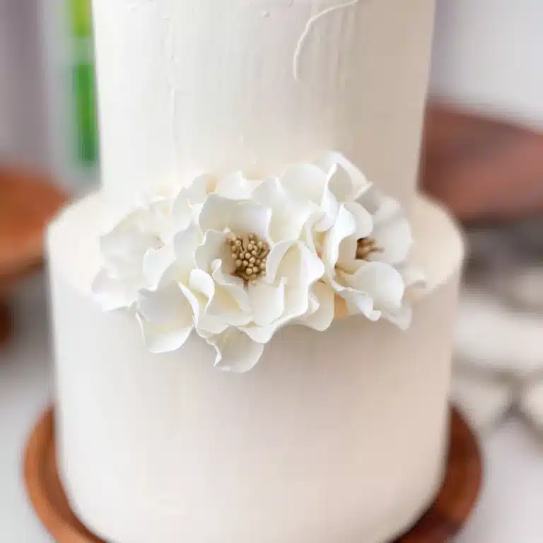 three white gold open roses decorating a two tier cake