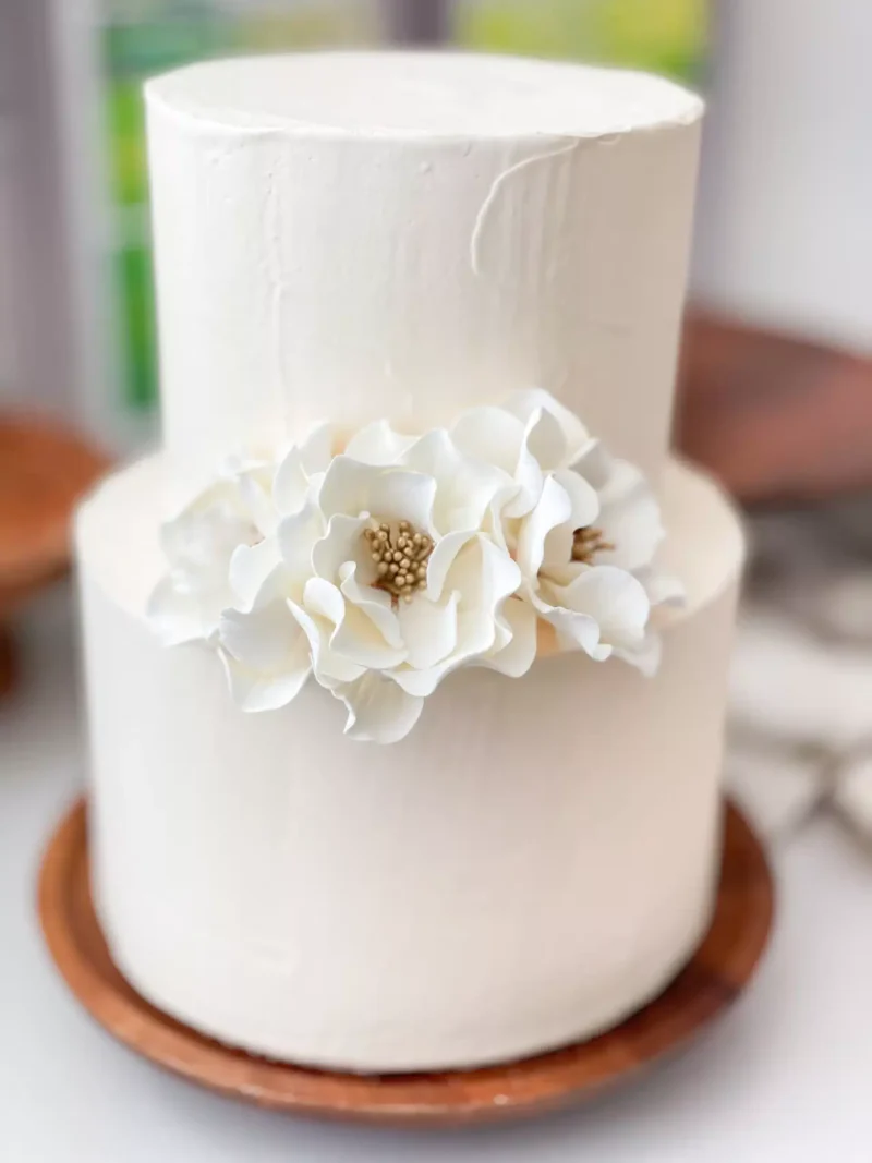 three white gold open roses decorating a two tier cake