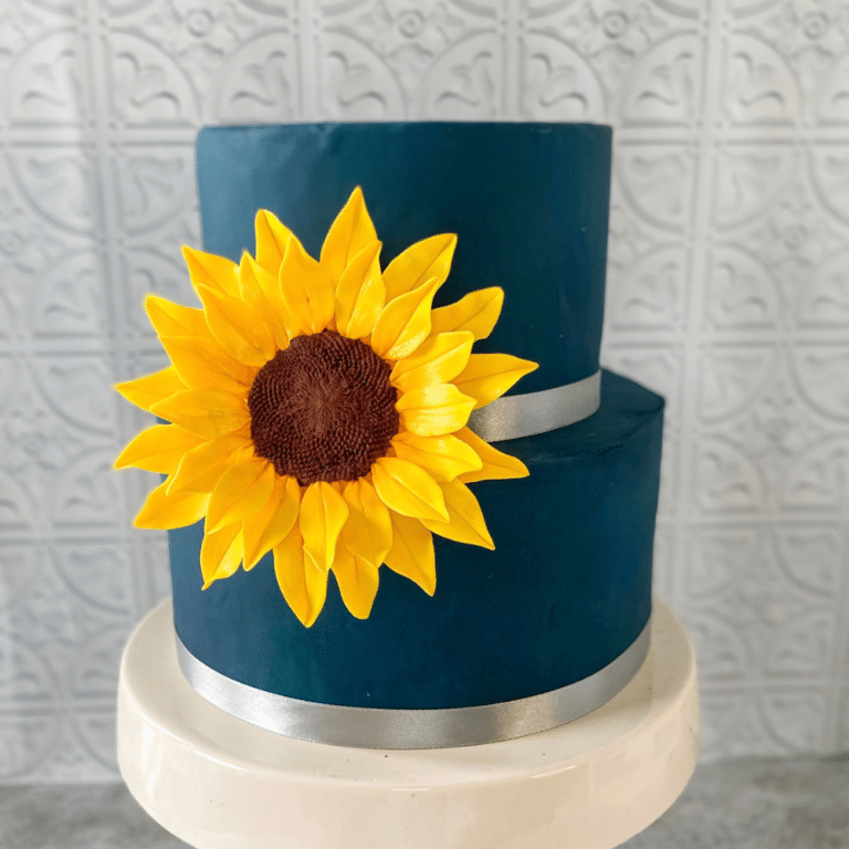Extra large sunflower sugar flower displayed on a navy blue cake