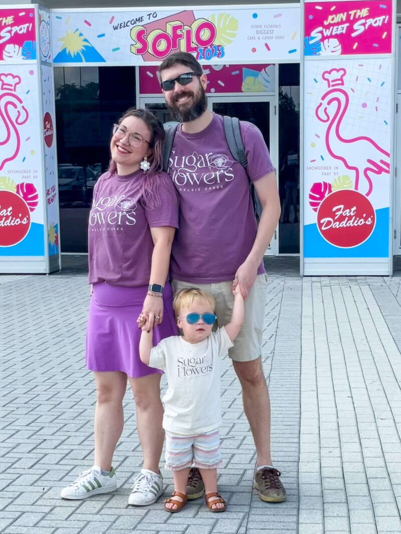 Sugar flowers by kelsie cakes tshirts Worn by a couple and their toddler standing in front of the soflo 2023 entrance
