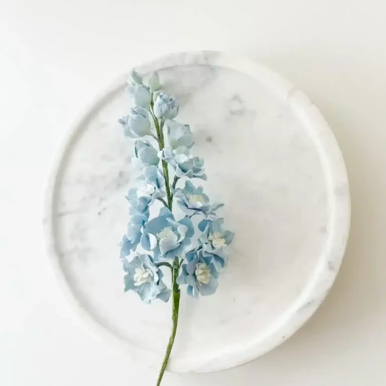 blue delphinium sugar flowers placed on marble cake stand