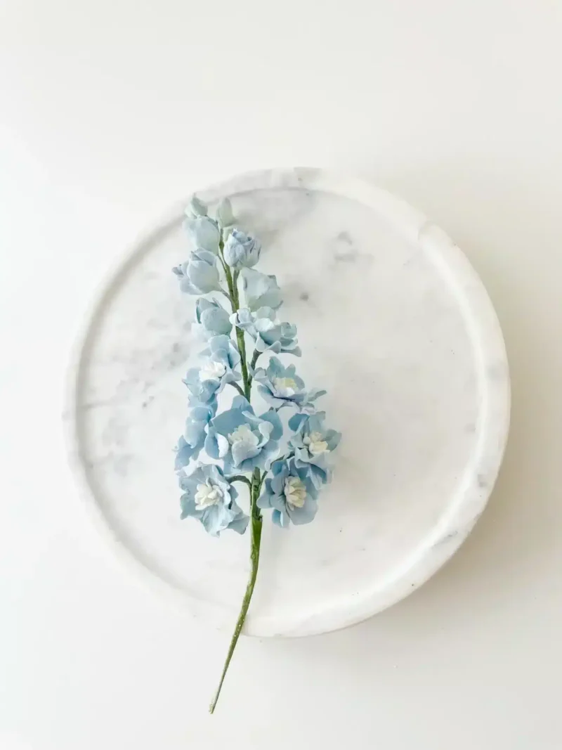 blue delphinium sugar flowers placed on marble cake stand