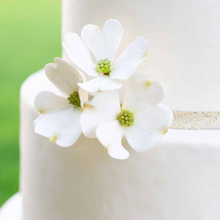 close up of a white cake with dogwood sugar flowers on top